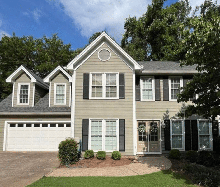 Two-story house with light green siding, a gray shingle roof, and multi-paned windows with black shutters