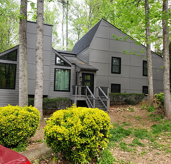 Modern gray house with black roof nestled among trees