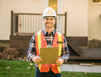 An exterior contractor posting infront of the camera with a house in the background